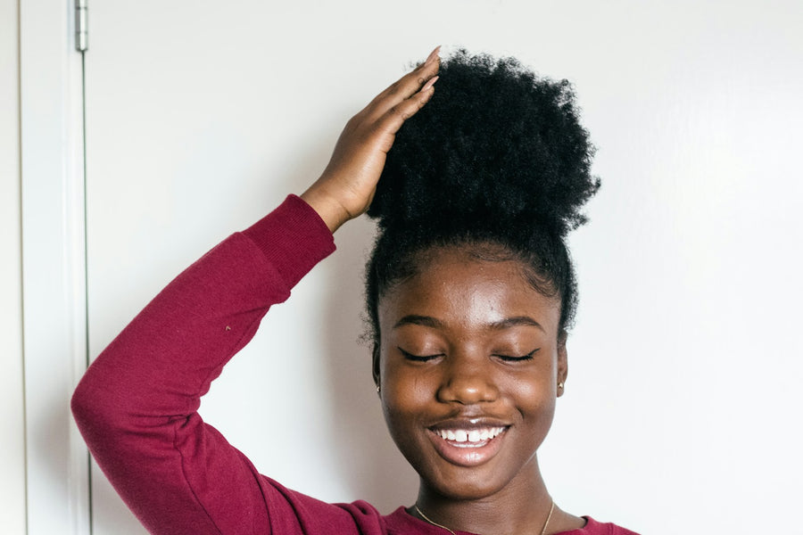 Trichologie - femme souriante touchant ses cheveux naturels